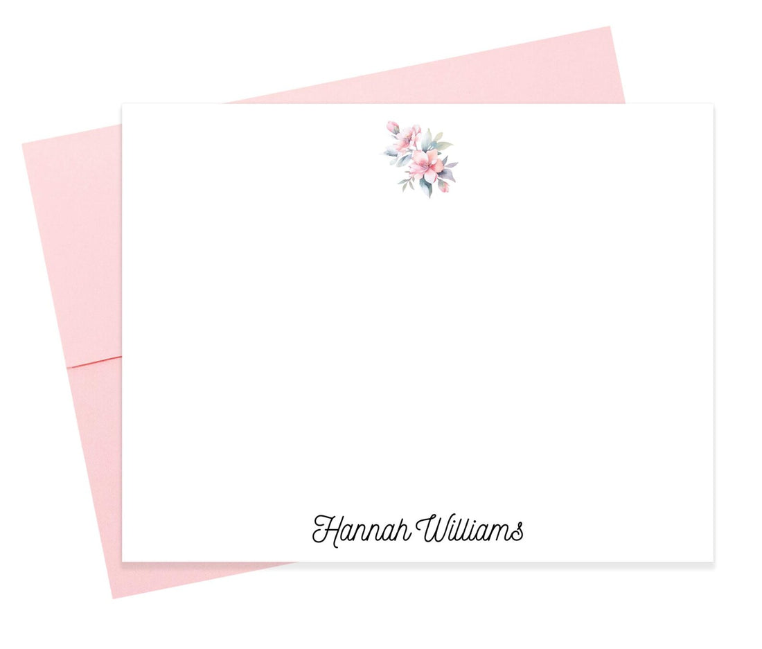 A blank white card with a pink envelope underneath, featuring a floral design on the top right corner.