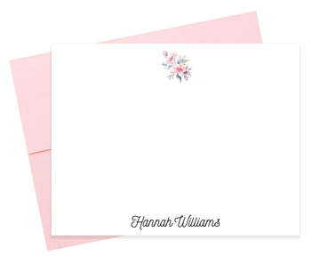 A blank white card with a pink envelope underneath, featuring a floral design on the top right corner.