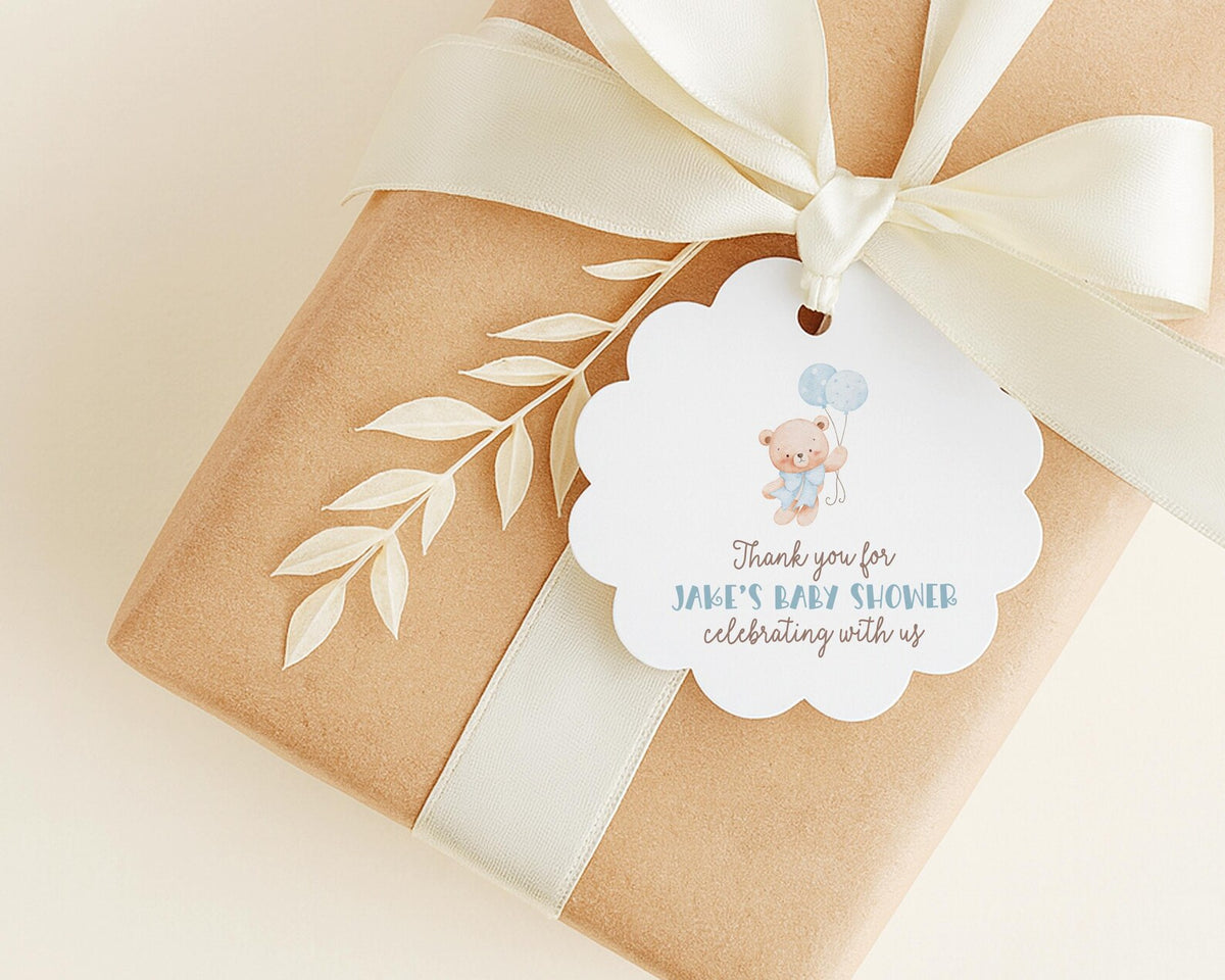 A brown gift box with a white ribbon and a white tag attached to it, featuring a teddy bear and the text "Thank you for Jake's baby shower celebrating with us".