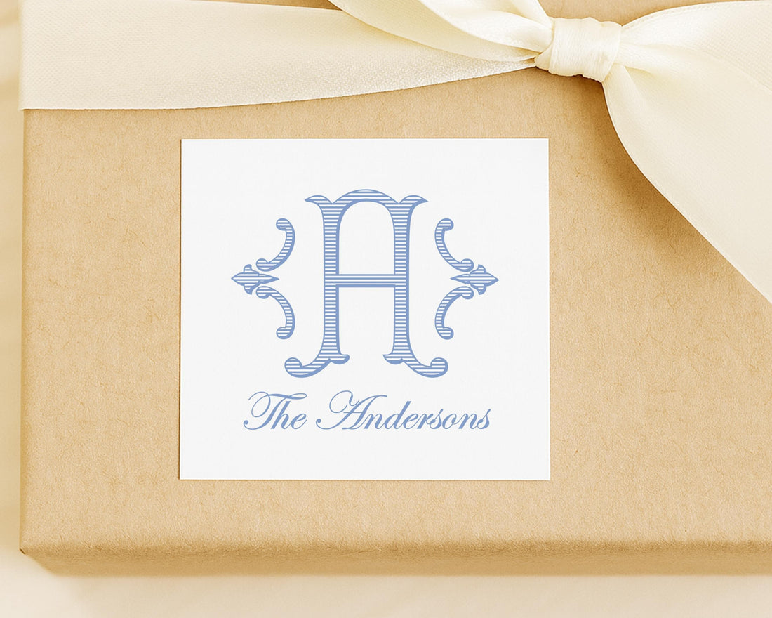A white label with a blue monogram and text, placed on a brown background with a white ribbon.