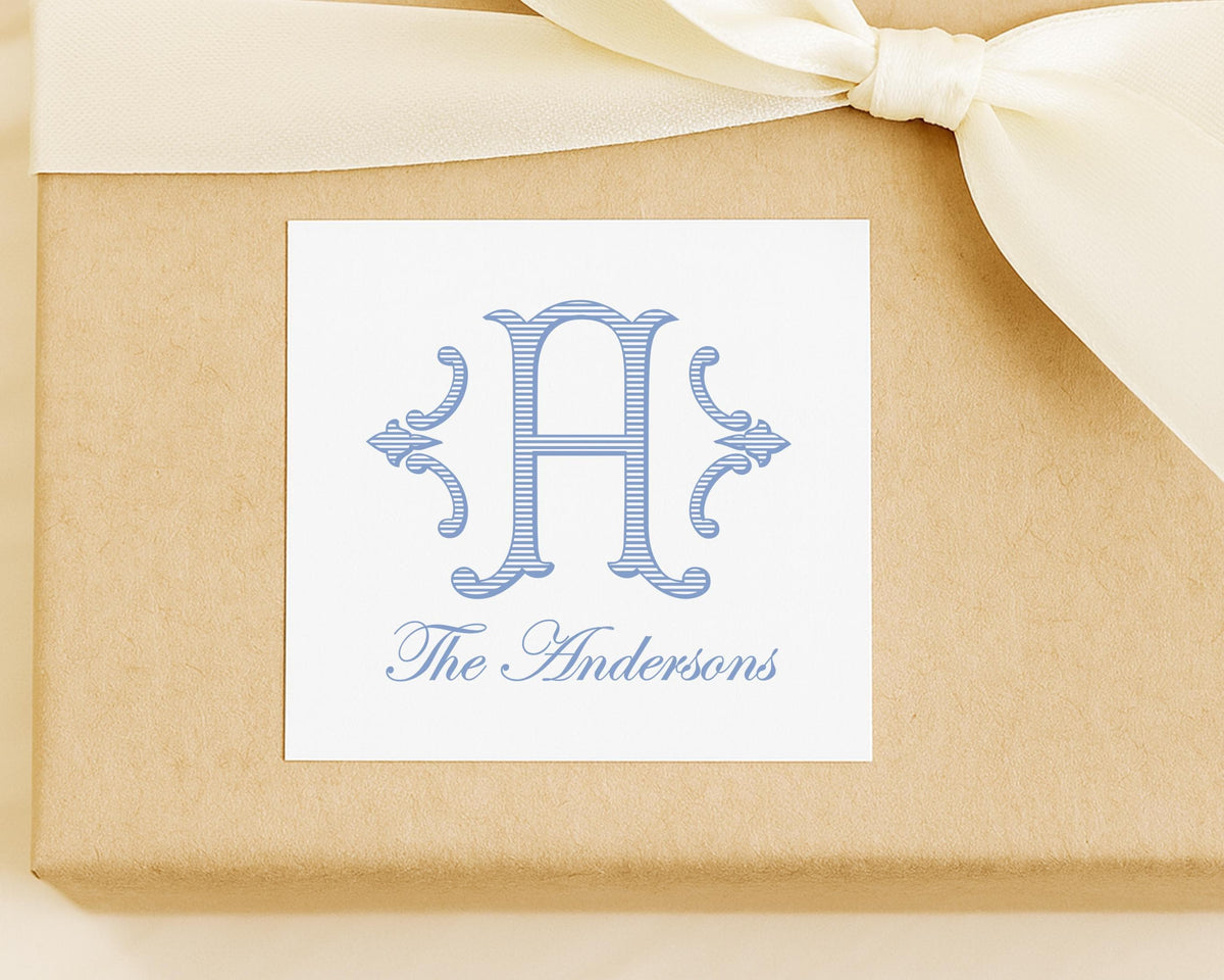 A white label with a blue monogram and text, placed on a brown background with a white ribbon.