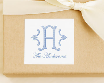 A white label with a blue monogram and text, placed on a brown background with a white ribbon.
