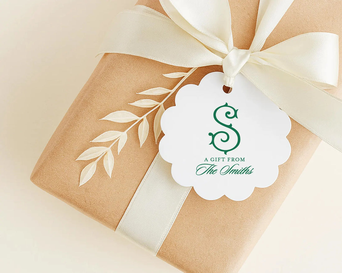 A gift wrapped in brown paper with a white ribbon and a scalloped edge, featuring a white tag with a green logo and text.