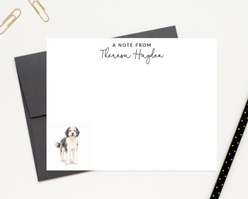 a personalized note card with a dog illustration on it, placed on a desk with a black envelope and a black pen.
