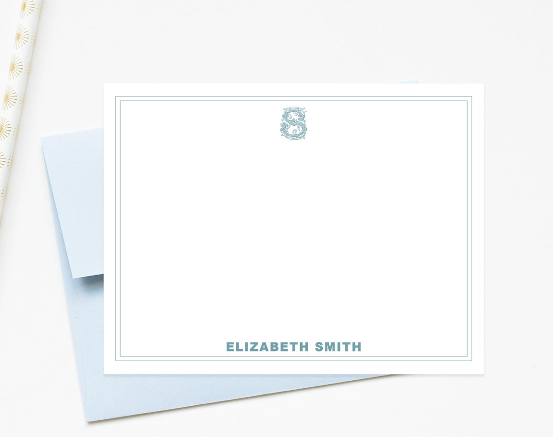 A blank white card with a blue border, featuring a monogrammed letter 'S' and the name 'ELIZABETH SMITH' printed on it.