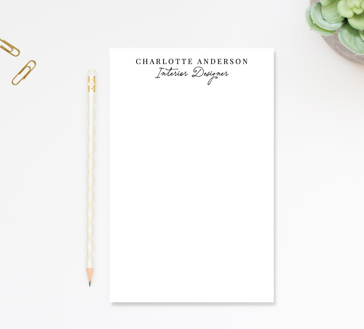a blank white notepad with the name "Charlotte Anderson" printed on it, along with a pencil and some office supplies.