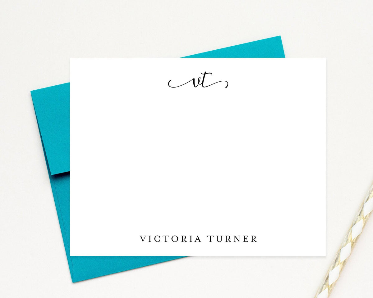 A white personalized note card with the name "Victoria Turner" written on it, placed on top of a teal envelope.