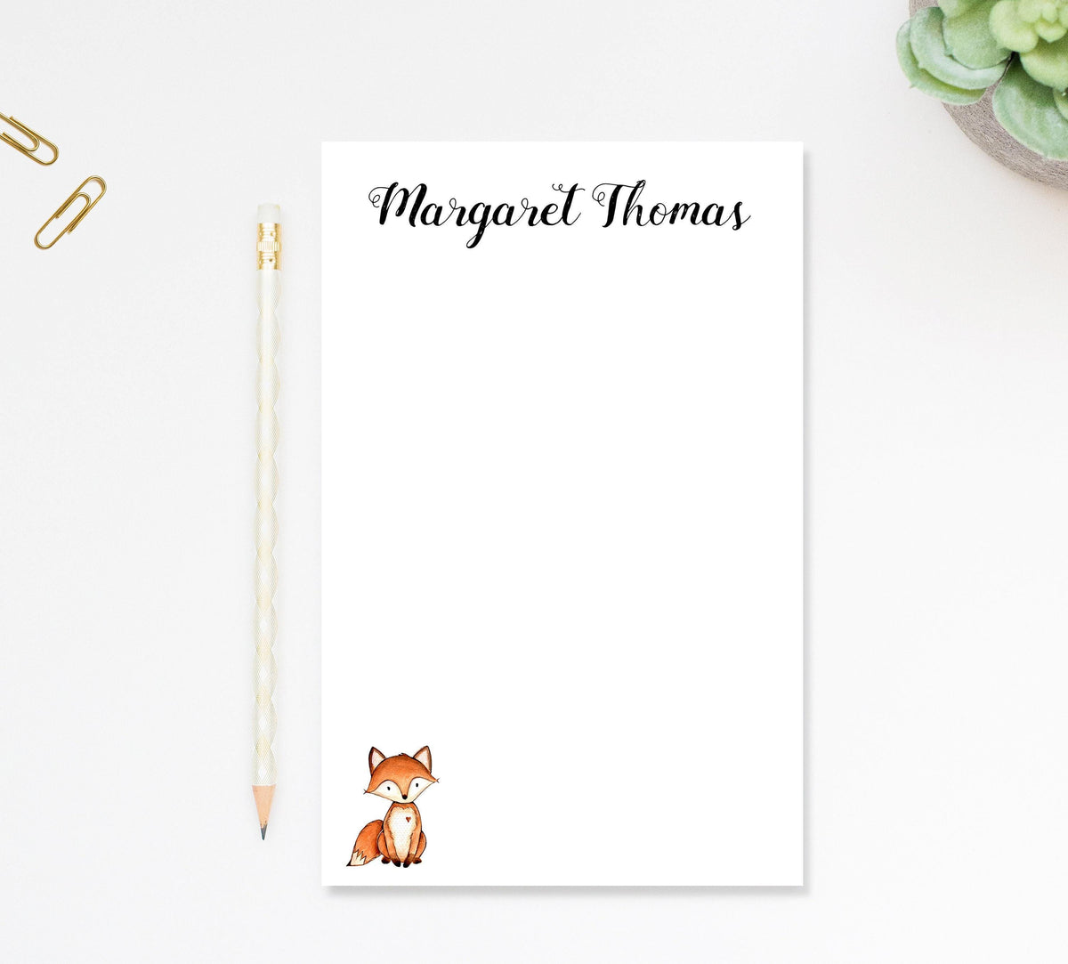 a blank nameplate with a fox illustration, accompanied by a pencil and a stapler on a white surface.