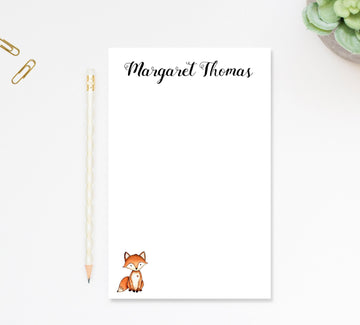 a blank nameplate with a fox illustration, accompanied by a pencil and a stapler on a white surface.