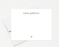 A white card with the name 'Emma Goldstein' printed on it, along with a small gold heart symbol.