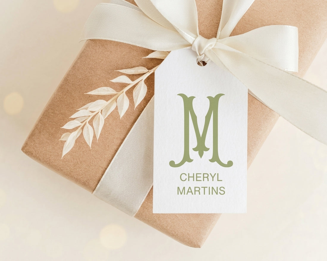 A brown gift box with a white ribbon and a white tag featuring a monogrammed letter "M" and the name "Cheryl Martins".