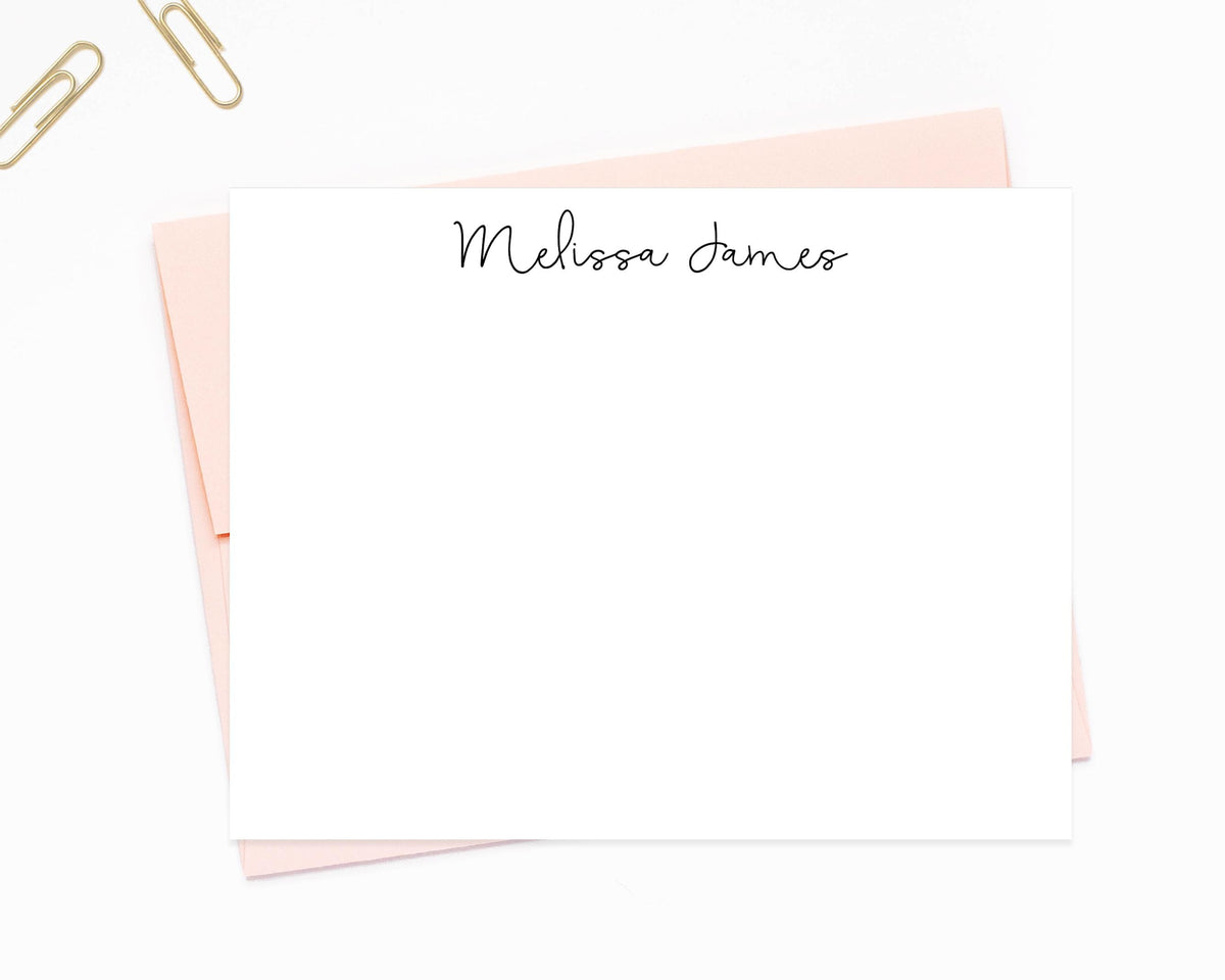 a blank personalized note card with the name "Melissa James" written on it, placed on top of a pink envelope.