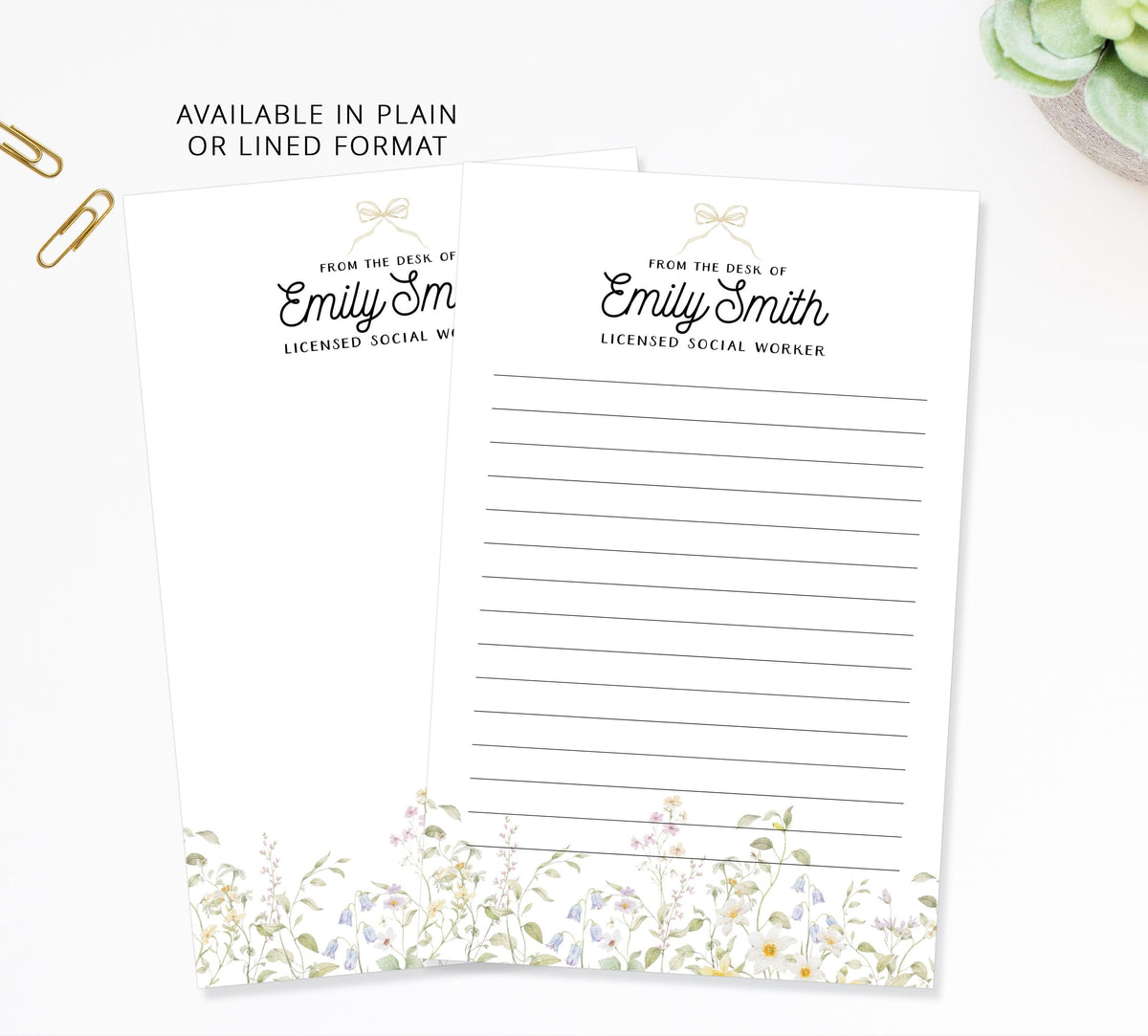 two blank lined paper sheets with a floral design on the bottom edge, placed on a white surface.