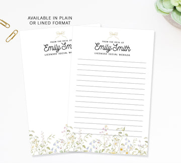 two blank lined paper sheets with a floral design on the bottom edge, placed on a white surface.