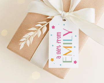 A gift wrapped in brown paper with a white ribbon and a tag that reads "a gift from Emily" with colorful stars and a leaf design.