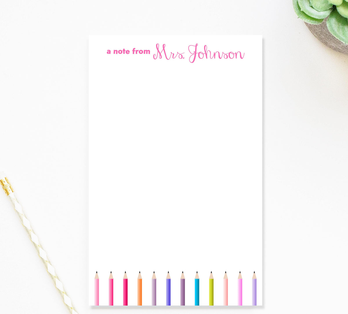 A blank note pad with a personalized message and a row of colorful pencils on the right side.