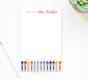 A blank note pad with a colorful design of crayons on the right side, and a note from "Mrs. Parker" written on the left side.