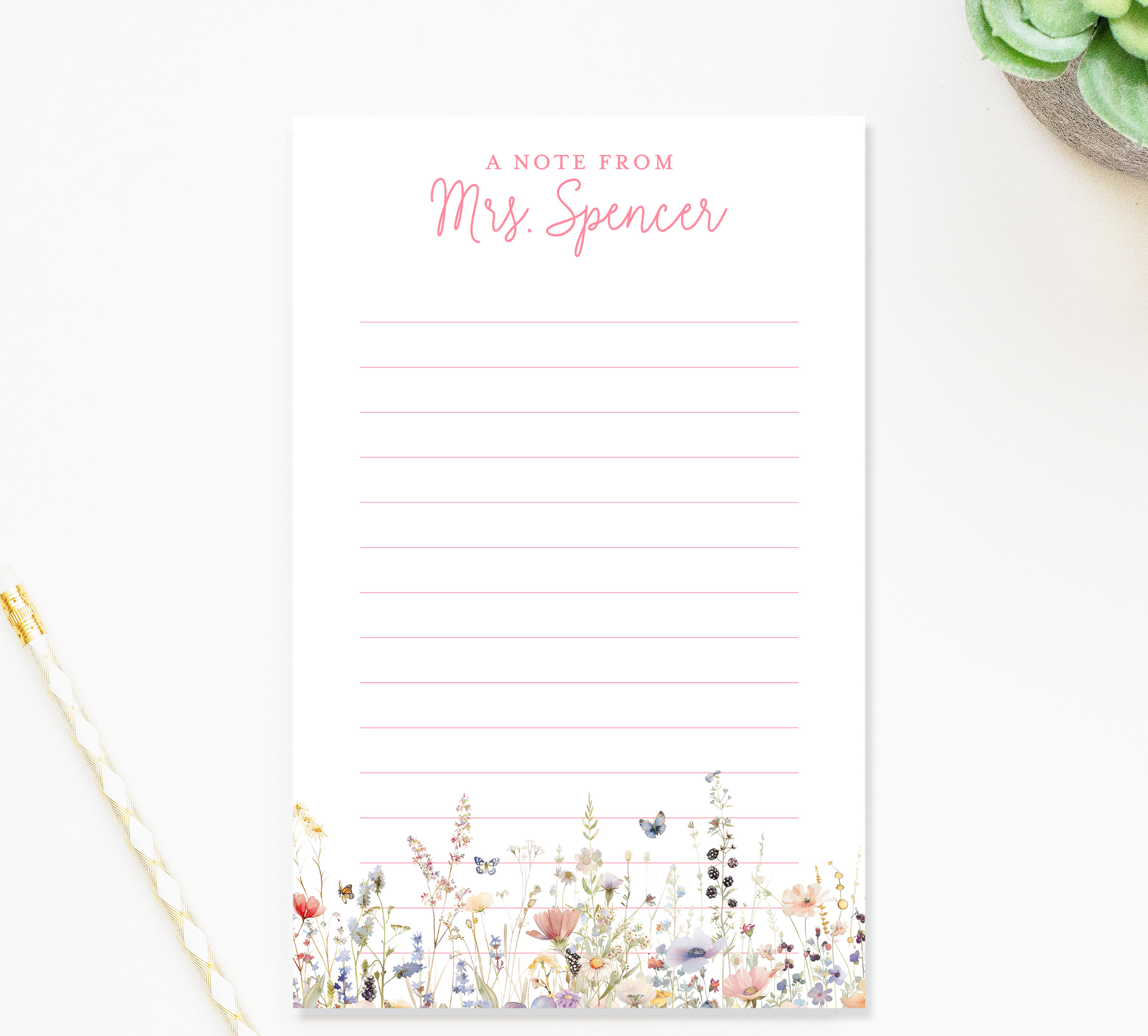 a blank lined notepad with a floral design on the cover, placed on a white surface next to a pen and a small green plant.