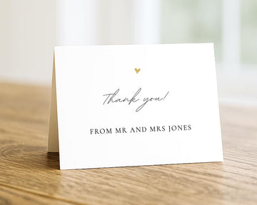 A white card with a gold heart and the text "Thank you! From Mr and Mrs Jones" is placed on a wooden surface.