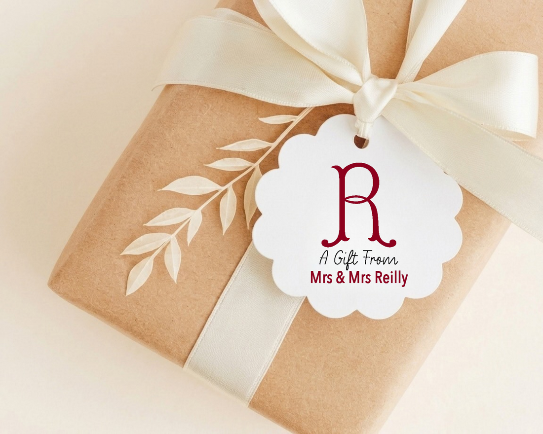 A brown gift box with a white ribbon and a white scalloped tag that reads "A Gift From Mrs & Mrs Reilly".