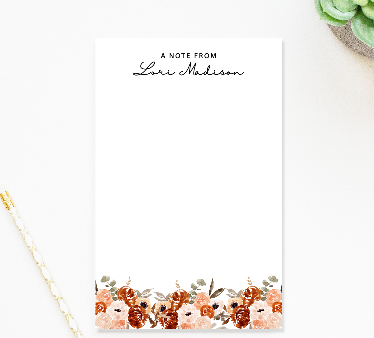 a blank note pad with a floral border, placed on a white surface.