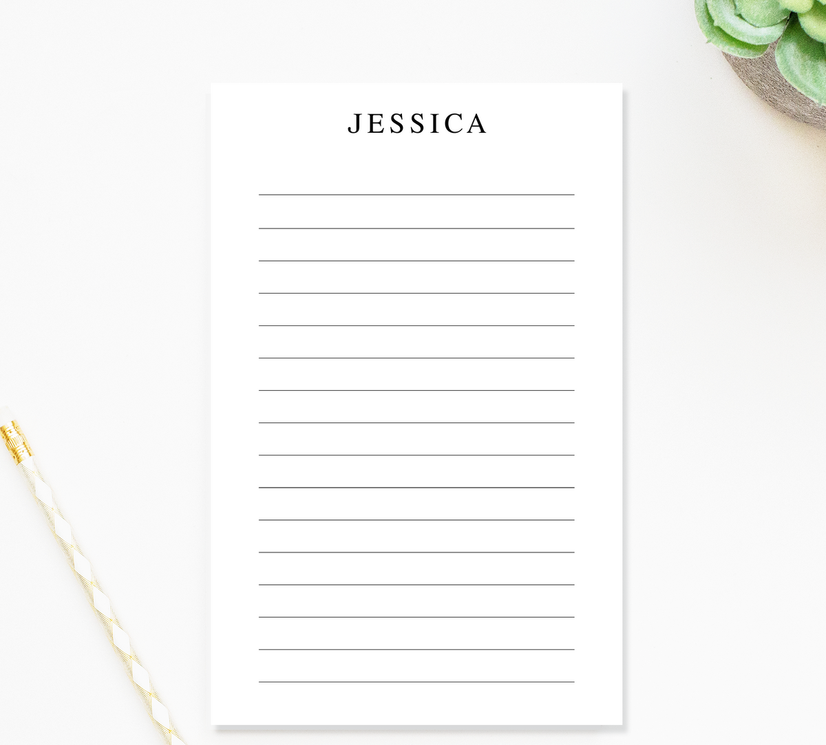 a blank lined notepad with the name "JESSICA" written on it, placed on a white surface next to a pen and a small green plant.