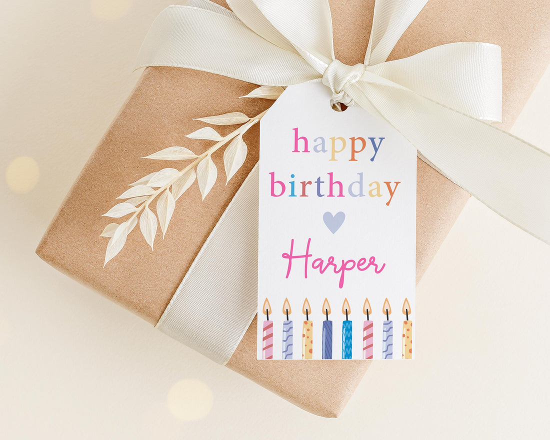 A brown gift box with a white ribbon and a birthday tag attached to it.