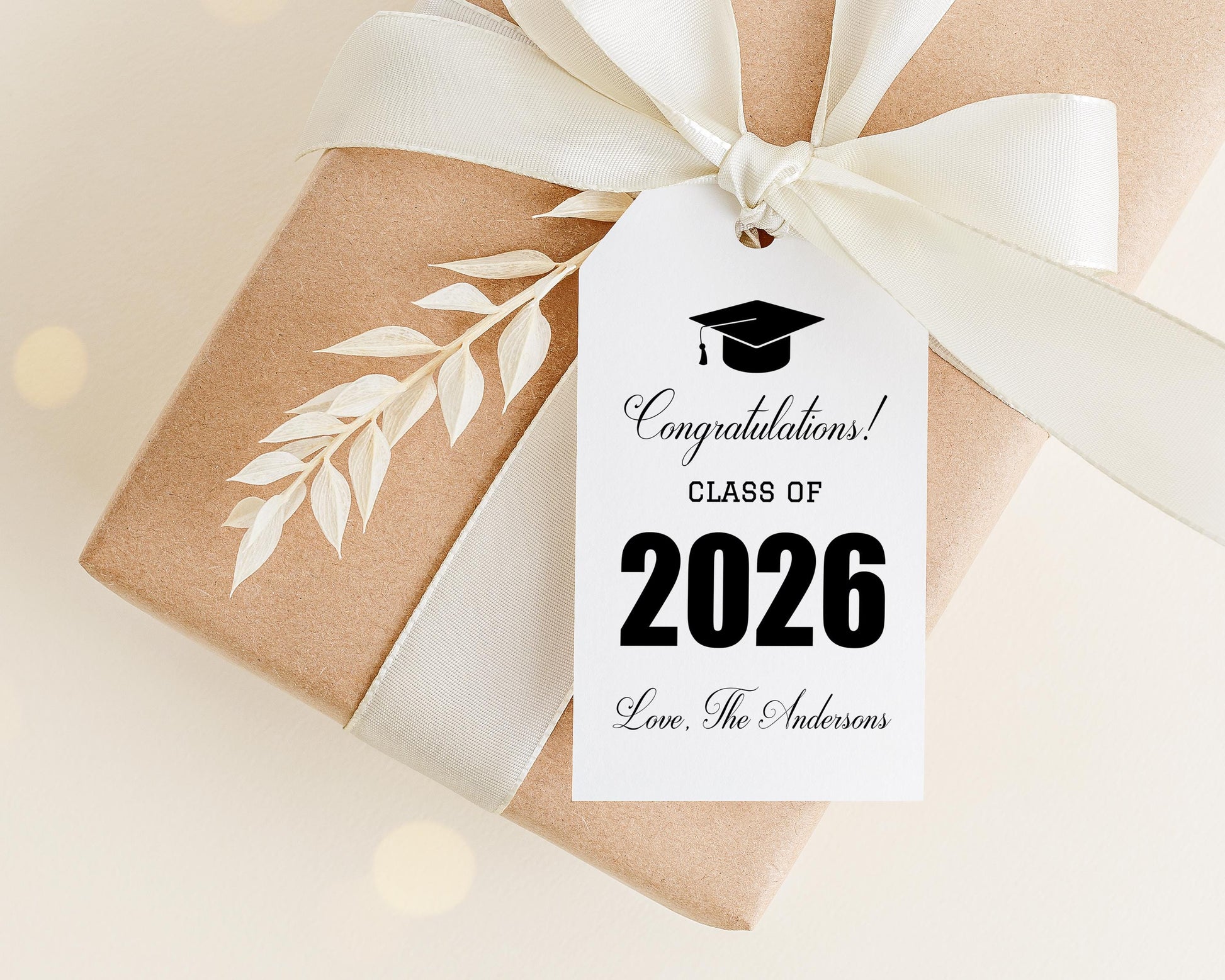 A gift box with a white ribbon and a graduation cap tag attached to it, celebrating the class of 2026.